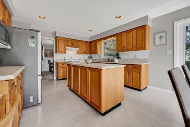 Kitchen with warm wood cabinetry, a central island, and stainless steel appliances.