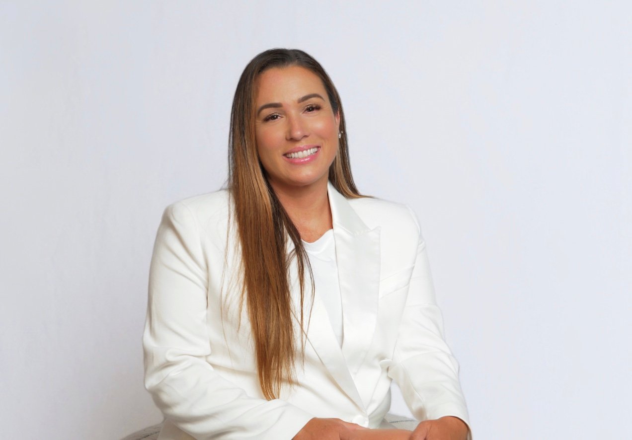 Rachel Espinosa in a white blazer, seated for a professional portrait.