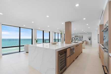 Modern kitchen with a white island and ocean views through floor-to-ceiling windows.
