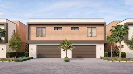Modern attached homes with brick upper facades, paired garages, and palm landscaping.