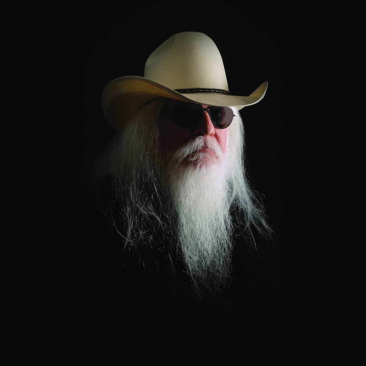 Leon Russell wearing a cowboy hat and sunglasses, with long white hair and a full white beard.
