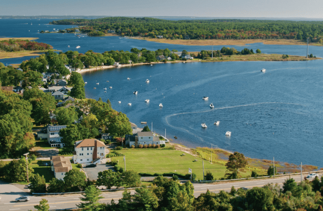 Aerial view of a waterfront neighborhood with boats scattered across a blue inlet.