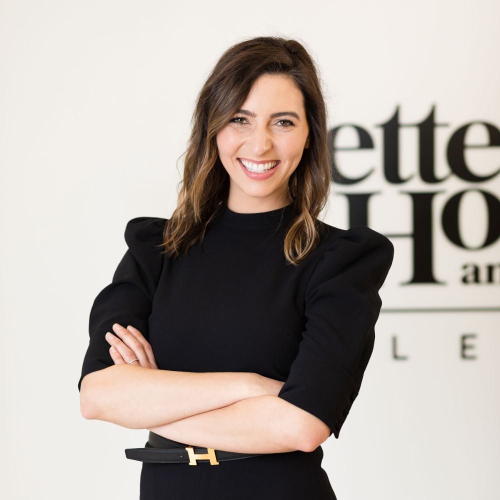 Jennifer Cesario smiles with her arms crossed, wearing a black outfit.