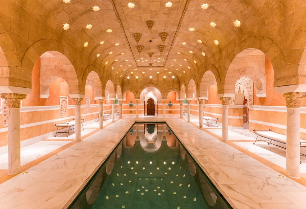 Indoor reflecting pool beneath an ornate vaulted ceiling with repeating stone arches.