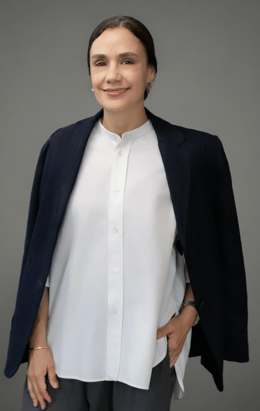 Julie Anidjar wearing a white blouse and dark jacket draped over her shoulders.