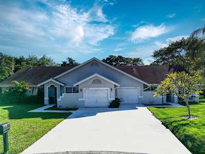 Single-story gray-blue home with an attached garage, broad driveway, and green lawn.