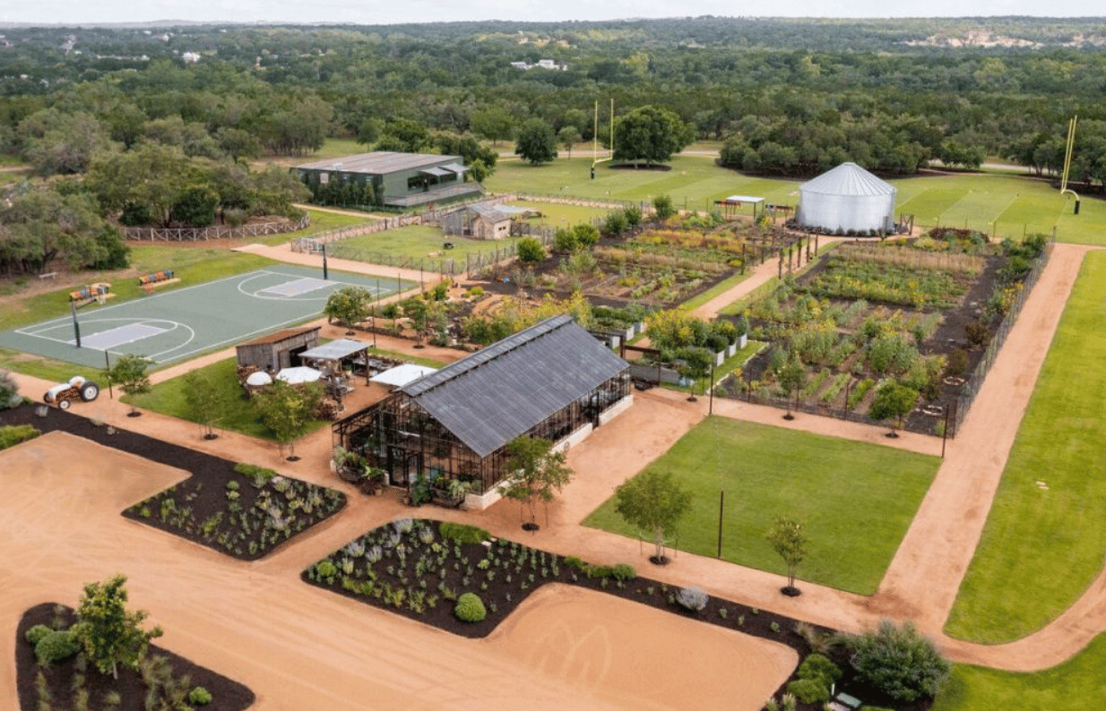 Aerial view of ranch club amenities with garden plots, sports courts, and a glass pavilion.