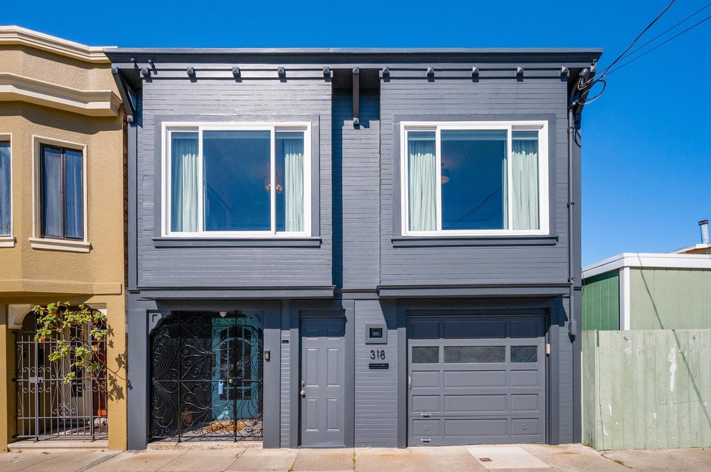 A street view of colorful single-family homes in San Francisco’s Excelsior District, with rolling hills in the background, representing the neighborhood’s August 2025 real estate market update.