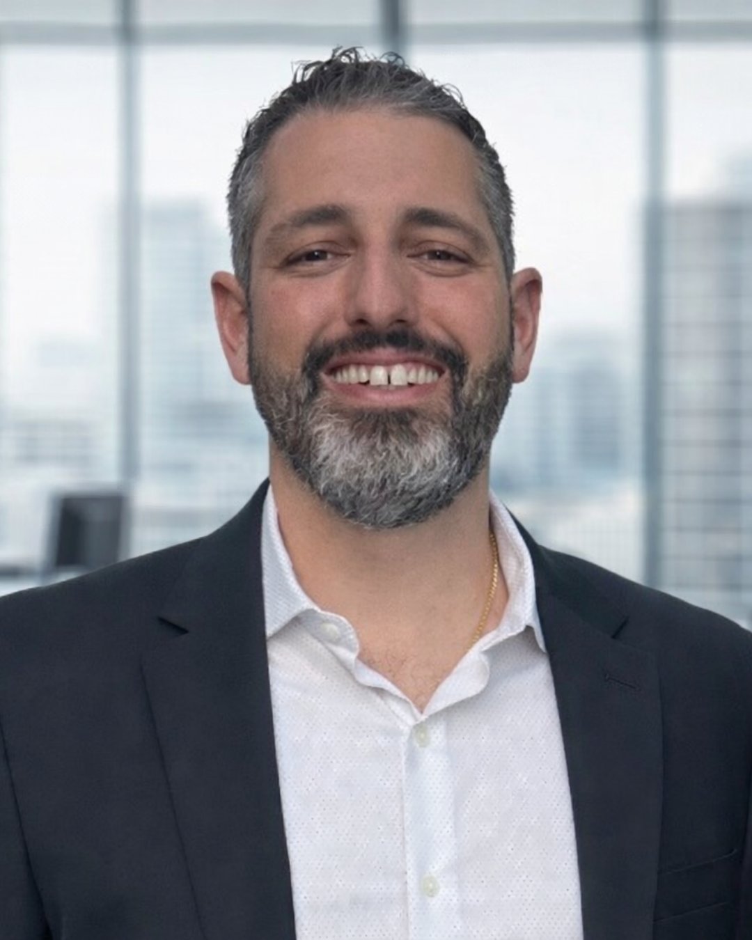Mason Bisi smiling in a dark suit jacket and white shirt.