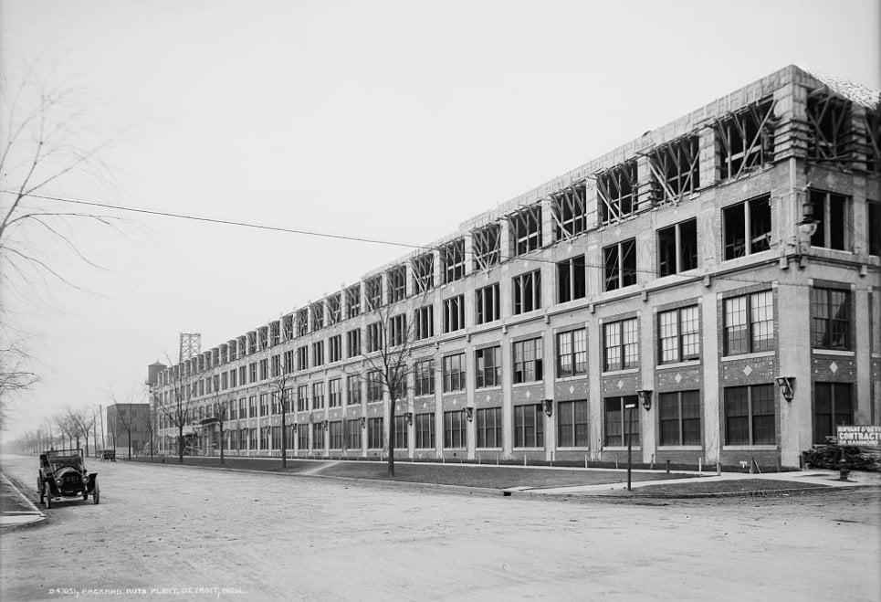 Historic Packard automobile plant in Detroit, with exposed upper-story framing and a vintage car.
