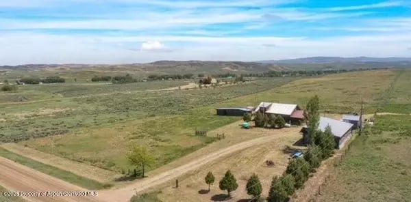 Rural property with farm buildings, a dirt drive, and expansive open fields near Craig.