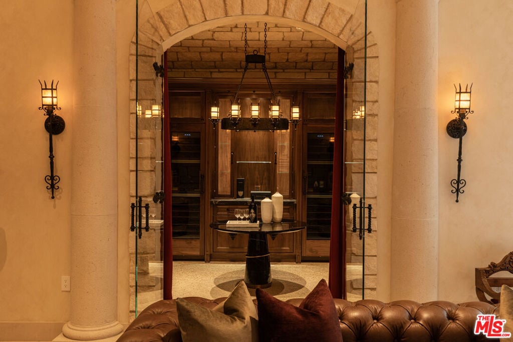 Wine cellar with dark wood cabinets and a tasting table behind glass doors.