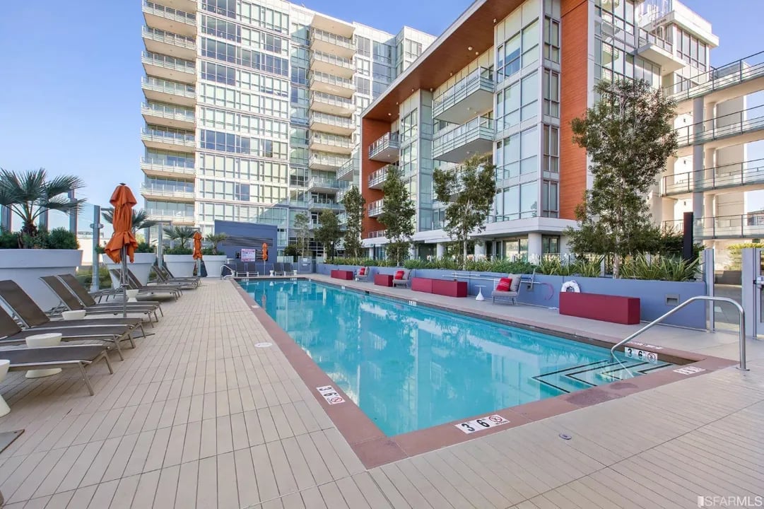 Arden Residences rooftop swimming pool with lounge chairs and the building's facade.