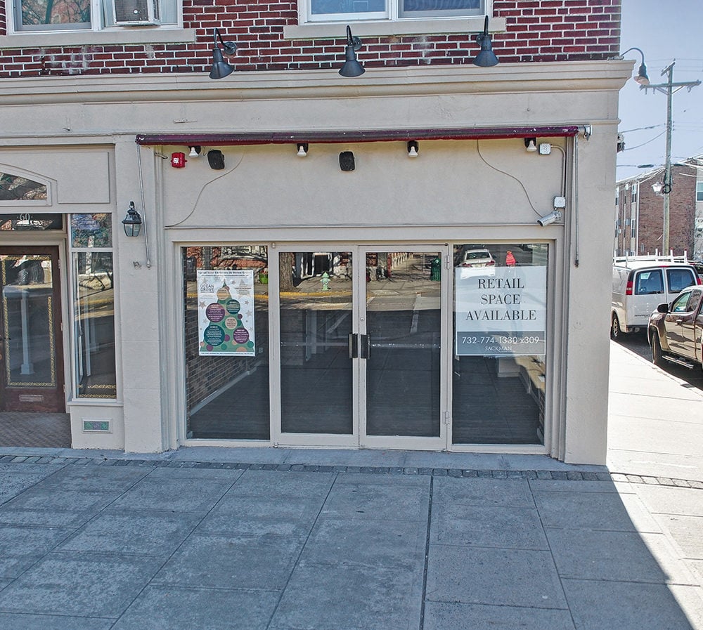 Retail storefront with glass doors and a sign advertising available space.