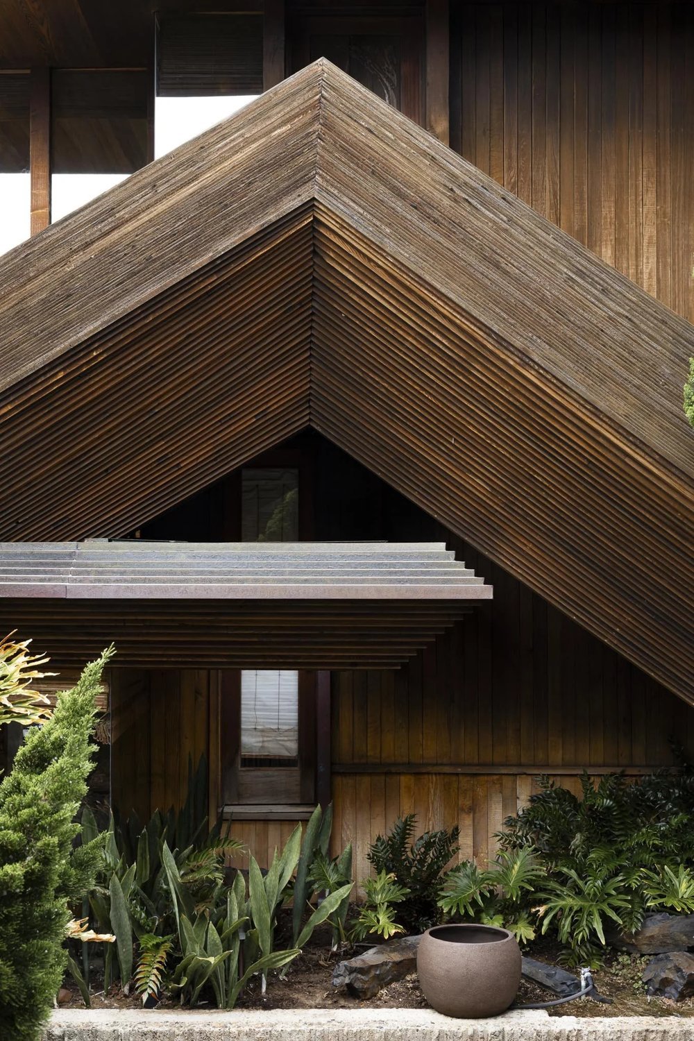 Close view of the stacked wood fascia forming a sharp chevron-shaped roof edge on the Kravis Residence.