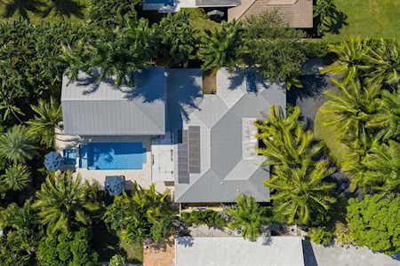 Aerial view of a home with a swimming pool surrounded by dense tropical landscaping.