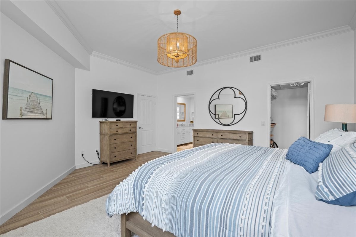 Bedroom with blue-and-white striped bedding, wood dressers, and a woven pendant light.