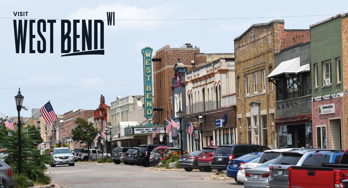 Downtown West Bend street view with the historic West Bend theater sign, parked cars, and storefronts.