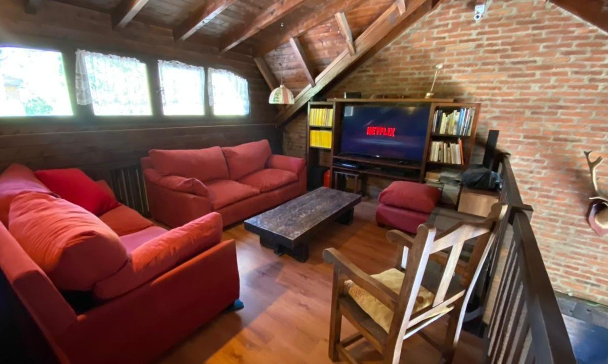 Furnished media room with red sofas, exposed timber beams, and a brick wall.