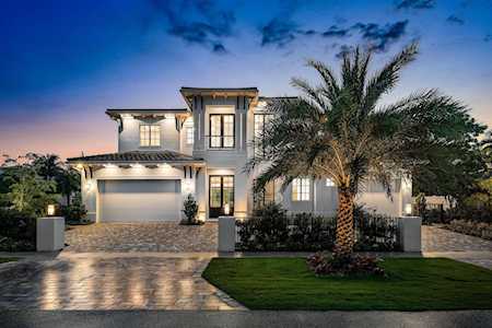 Modern two-story home at dusk with a broad driveway and a large palm tree.