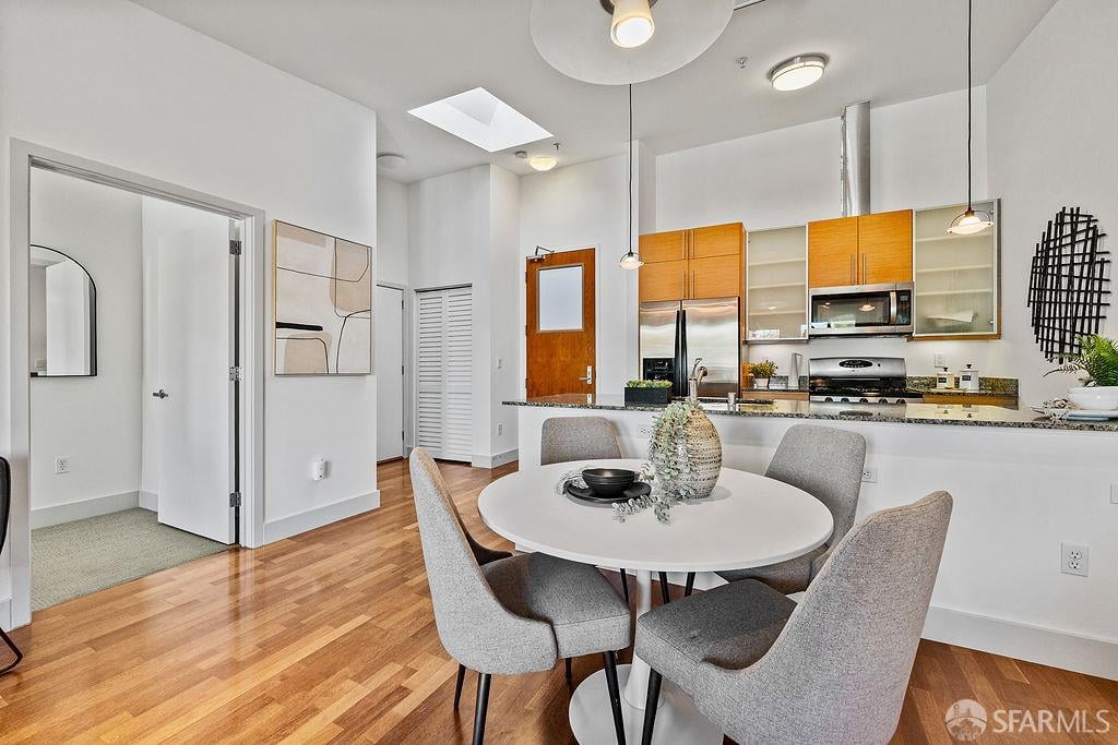 Open kitchen and dining area with warm wood cabinets, stainless appliances, and a round table.