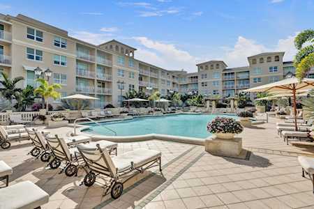 Courtyard swimming pool with lounge chairs and umbrellas beside a multi-story residential building.