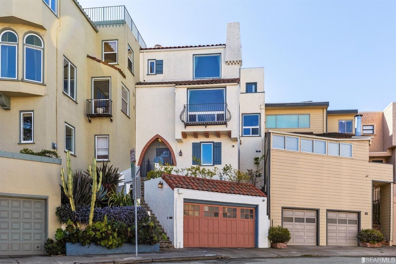 San Francisco residence with cream stucco, balconies, landscaped steps, and a red garage door.