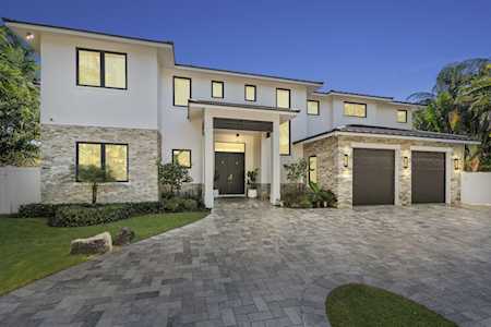 Modern two-story home with stone accents, a covered entry, and a wide paver driveway.