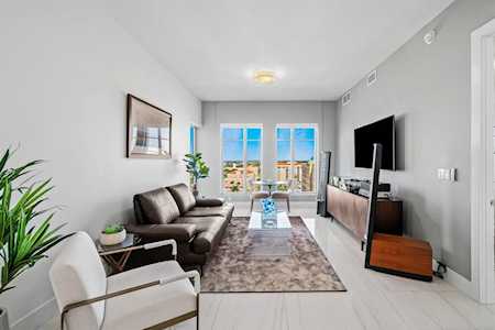 Furnished living room with a leather sofa, white accent chair, and balcony doors.