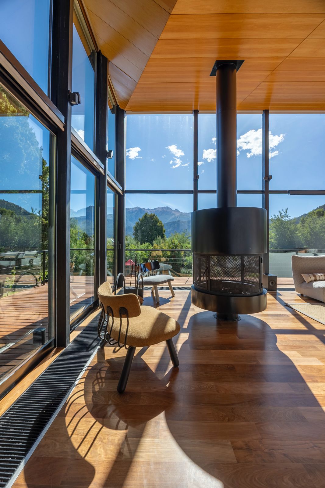 Living room with a suspended fireplace, floor-to-ceiling windows, and mountain views.