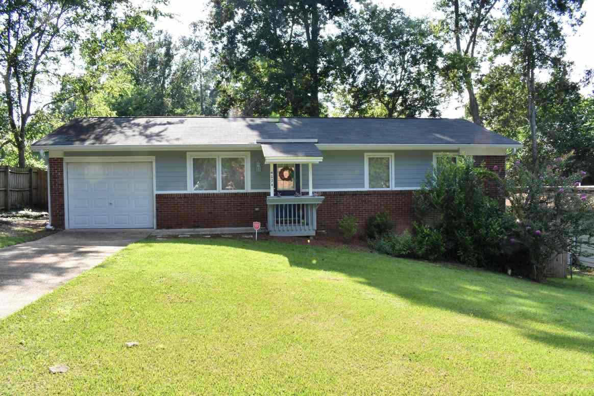 A brick home featuring a garage and a well-maintained lawn, showcasing a welcoming suburban environment.