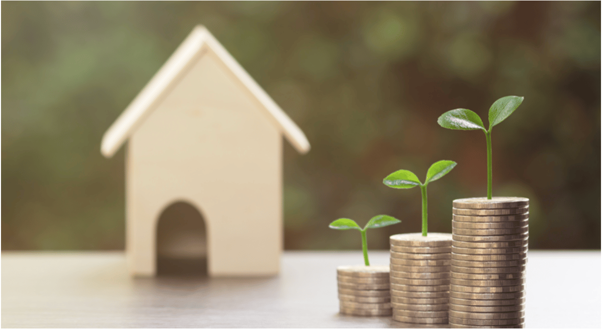Coin stacks with growing seedlings beside a small model house.
