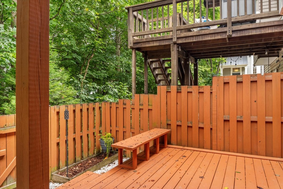Fenced wooden backyard deck with a built-in bench beneath an elevated deck.