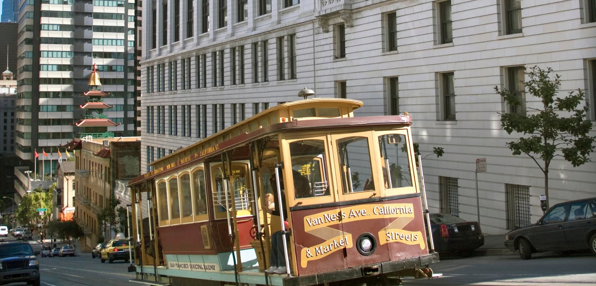 A historic San Francisco cable car climbing the hills of Pacific Heights, with passengers enjoying the ride and the picturesque surroundings.