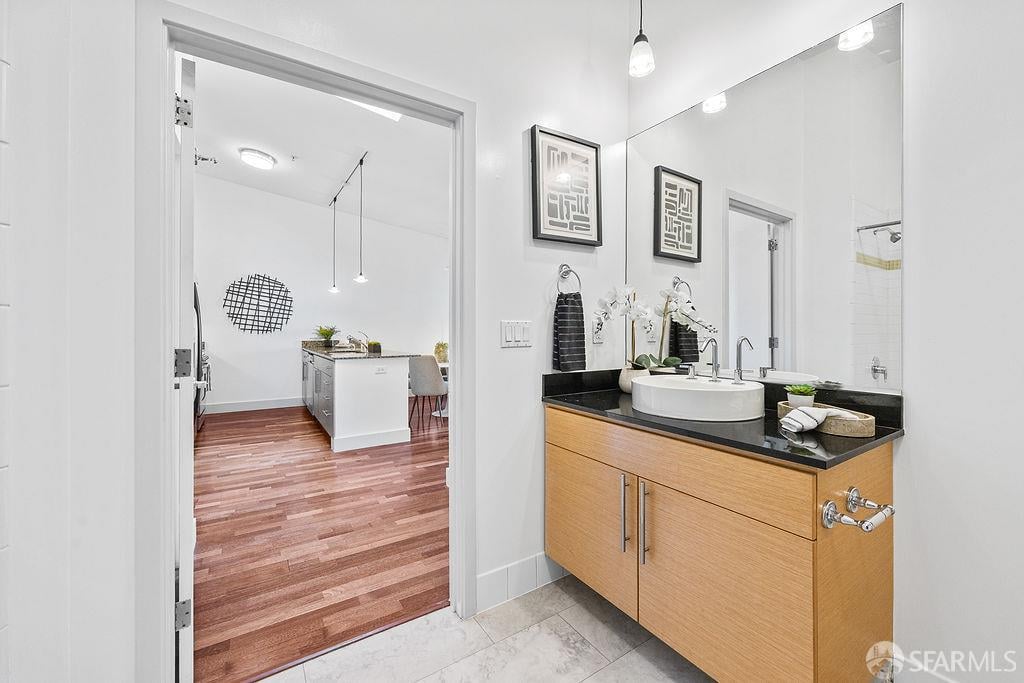 Bathroom with a wood vanity and vessel sink, opening onto a kitchen.