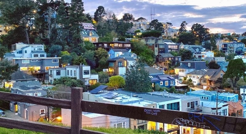A view of the Noe Valley neighborhood from atop Billy Goat Hill at dusk, with hillside homes lit up beneath a pastel evening sky.