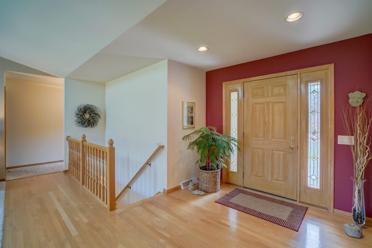 Home entryway with a light wood front door, glass sidelights, and red accent wall.