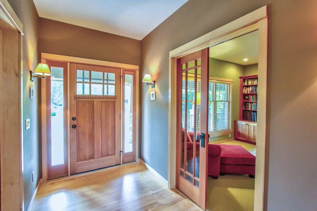 Entry foyer with a paneled wood door and glass-paned doors opening to a red-seated sitting room.