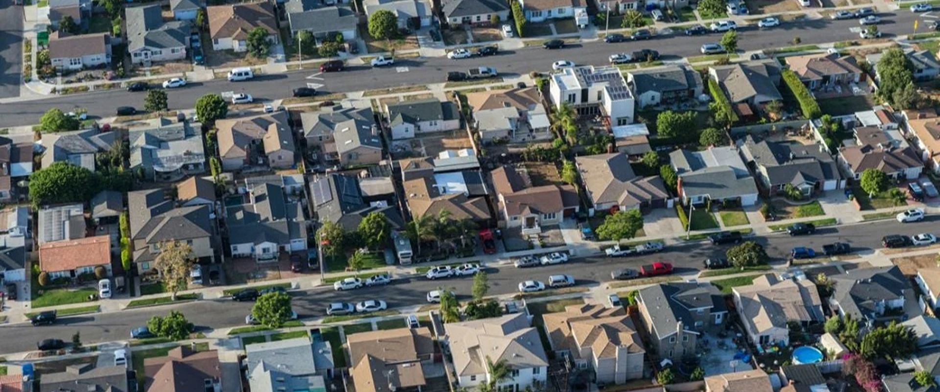 Aerial view of a residential neighborhood with rows of homes and a backyard pool.