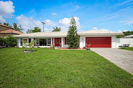 Single-story white home with a red front door and garage, front lawn, and concrete driveway.
