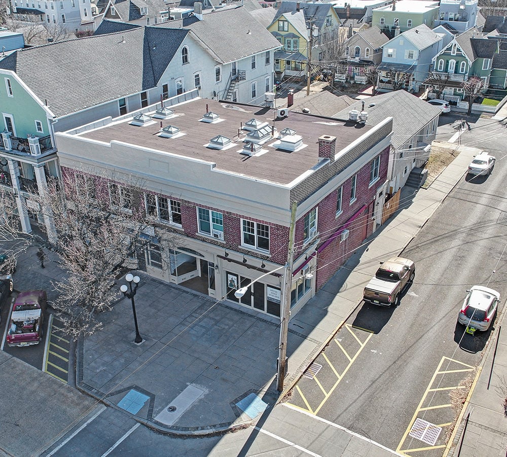 Aerial view of a corner commercial building with a flat roof, skylights, and red brick facade.