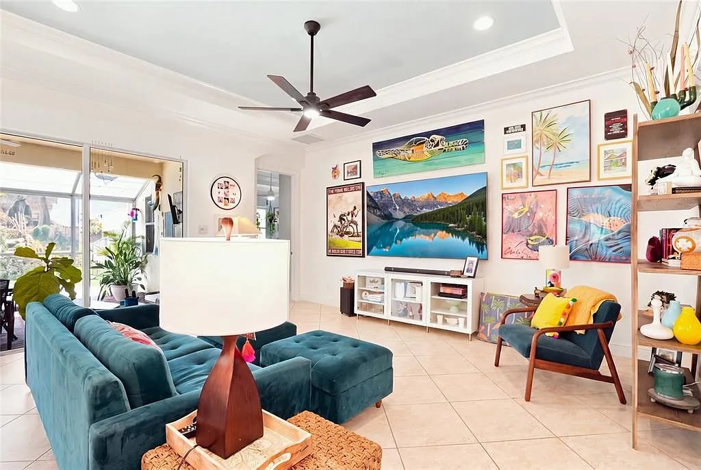 Living room with a teal sectional, colorful wall art, and glass doors to a patio.