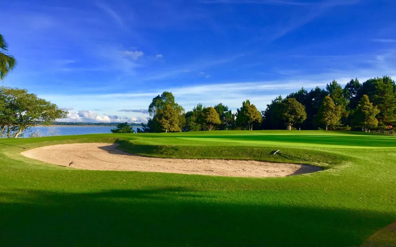 A serene golf course surrounded by lush greenery and vibrant blue skies.