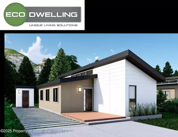 Modern white-and-gray home with a low-pitched roof, mountain backdrop, and paved entry path.