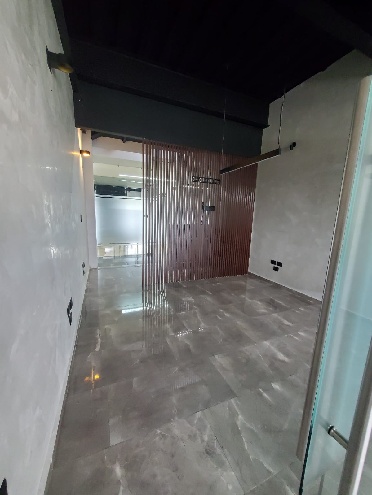Vacant office with polished gray tile flooring and a vertical wood-slat partition.