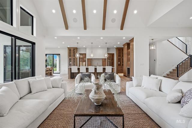 Living room with white sofas, vaulted wood-beam ceiling, and an open view of the kitchen.