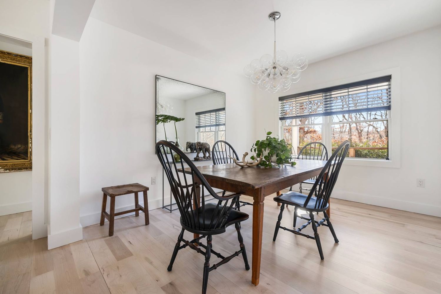 Dining room with a dark wood table, black chairs, large mirror, and wide windows.