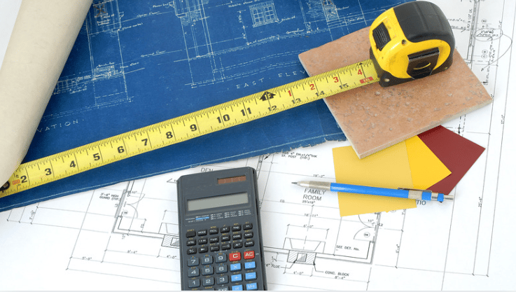Blueprints with a tape measure, calculator, and paint color samples.
