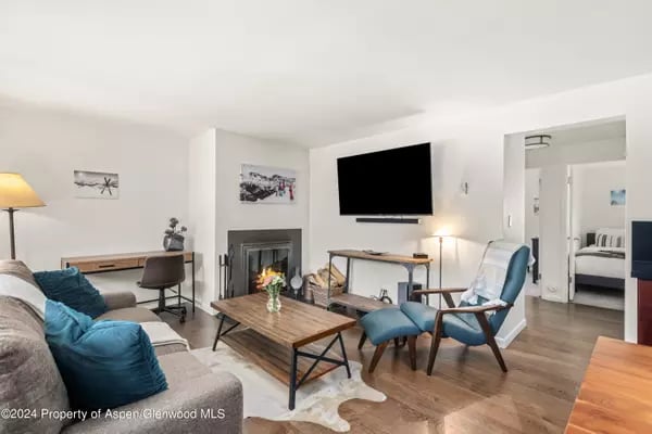 Living room with a fireplace, wall-mounted television, and teal lounge chair.