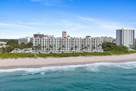 Beachfront condominium complex along a sandy beach, viewed from above with turquoise ocean in the foreground.